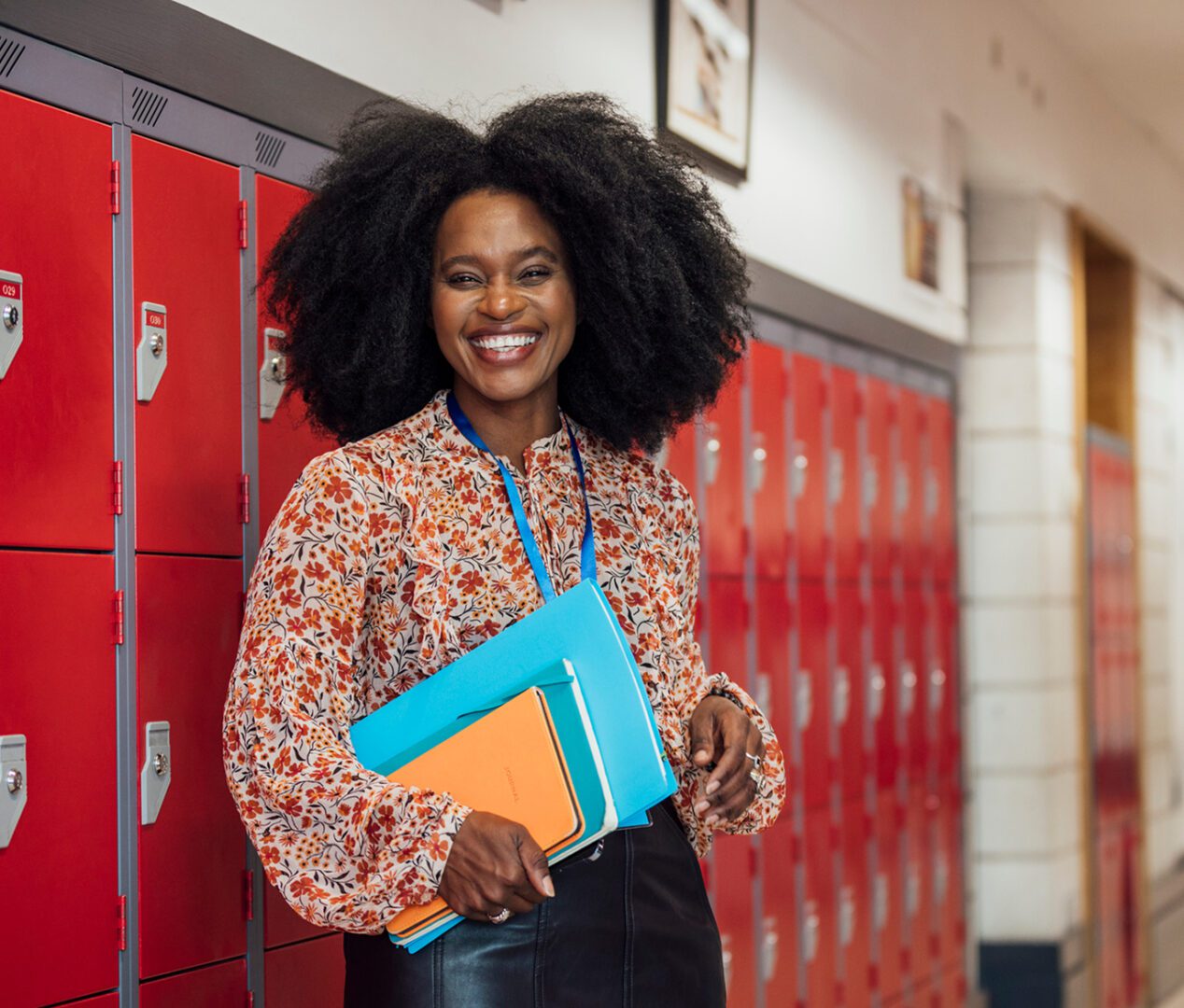 Educator with curly hair and colorful folders.
